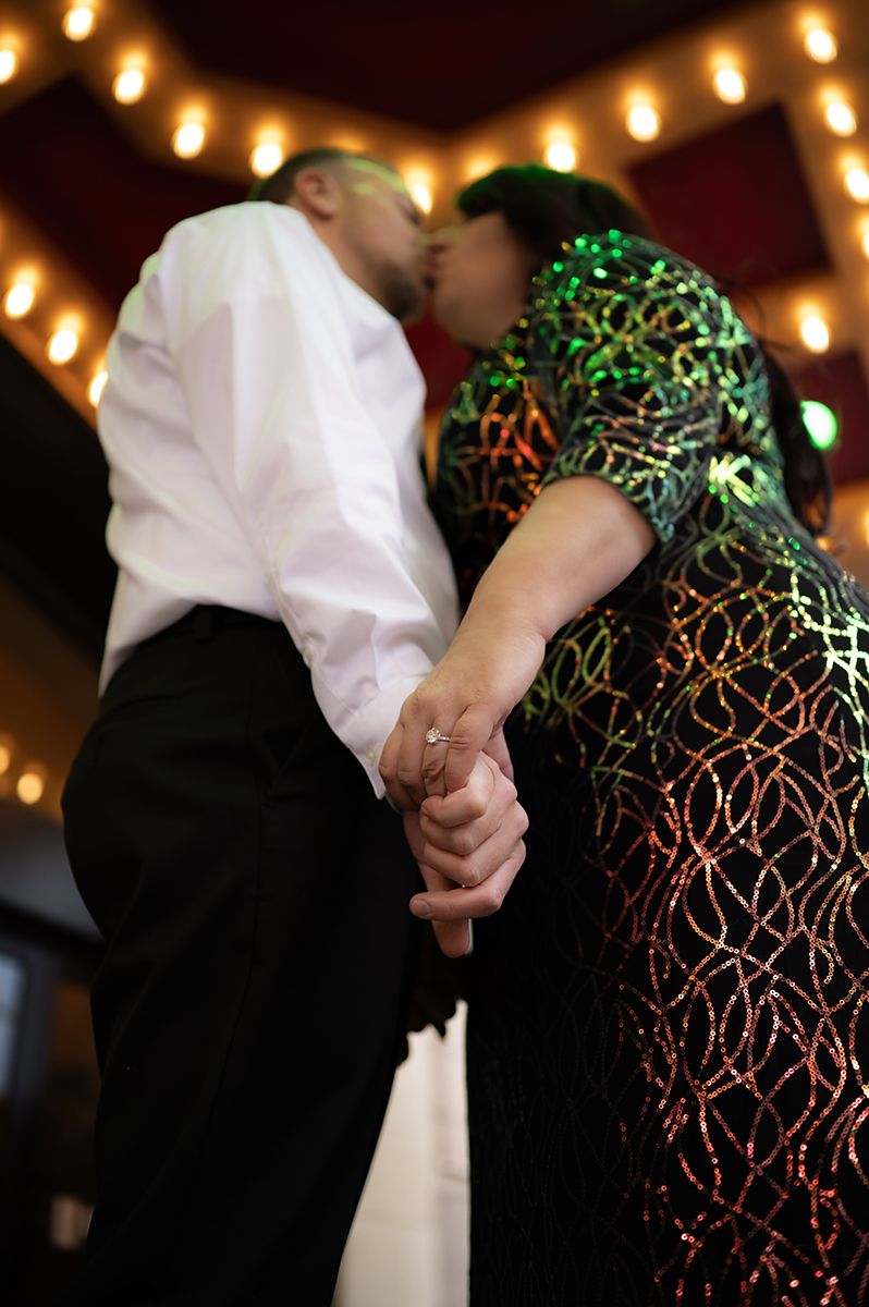 male wearing suit kisses female wearing shiny dress while holding hands at playhouse square Cleveland Ohio